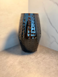 Front view of a handmade black glazed ceramic vase with carved chevron screen work pattern in vertical columns, photographed against a marble background
